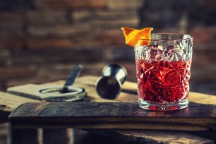 Cocktail Negroni on a old  wooden board. Drink with gin, campari martini rosso and orange.